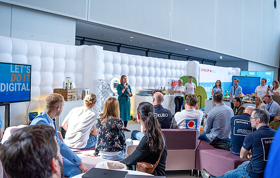 Das Bild zeigt Sandra Boser, Staatssekretärin im Ministerium für Kultus, Jugend und Sport, die zu den Anwesenden des Netzwerktreffens spricht. Die Anwesenden sitzen auf Sofas im Vordergrund. 