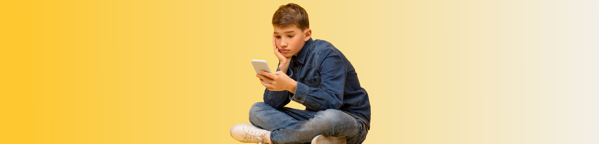 LMZ Spotlight KI-Chatbots Teenager-Junge sitzt im Schneidersitz und starrt angestrengt auf ein Handy