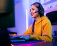 Selbstlernkurs Gaming Teenager-Mädchen mit Headset sitzt an einem Gaming-Computer und auf einem Gaming-Stuhl.