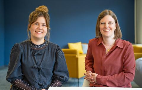 Man sieht zwei Mitarbeitende der Medienpaedagogischen Beratungsstelle des Landesmedienzentrums. Sie sitzen an einem Tisch und laecheln in die Kamera.