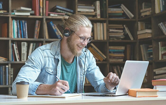 Junger Mann sitzt vor seinem Laptop in einer Videokonferenz Junger Mann sitzt vor seinem Laptop in einer Videokonferenz