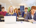 Jugendliche vor ihren Laptops in einer Schulklasse.