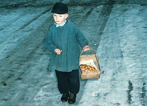 Kinderschüler im Blauhemd beim "Klopfen". Im Korb das Hefezöpfchen seiner "Dote", (Patin), 1955. Fotografie von Eugen Sauter.