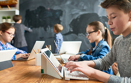 Schüler arbeitet mit seinem iPad im Klassenzimmer und gibt etwas mit der Tastatur ein.